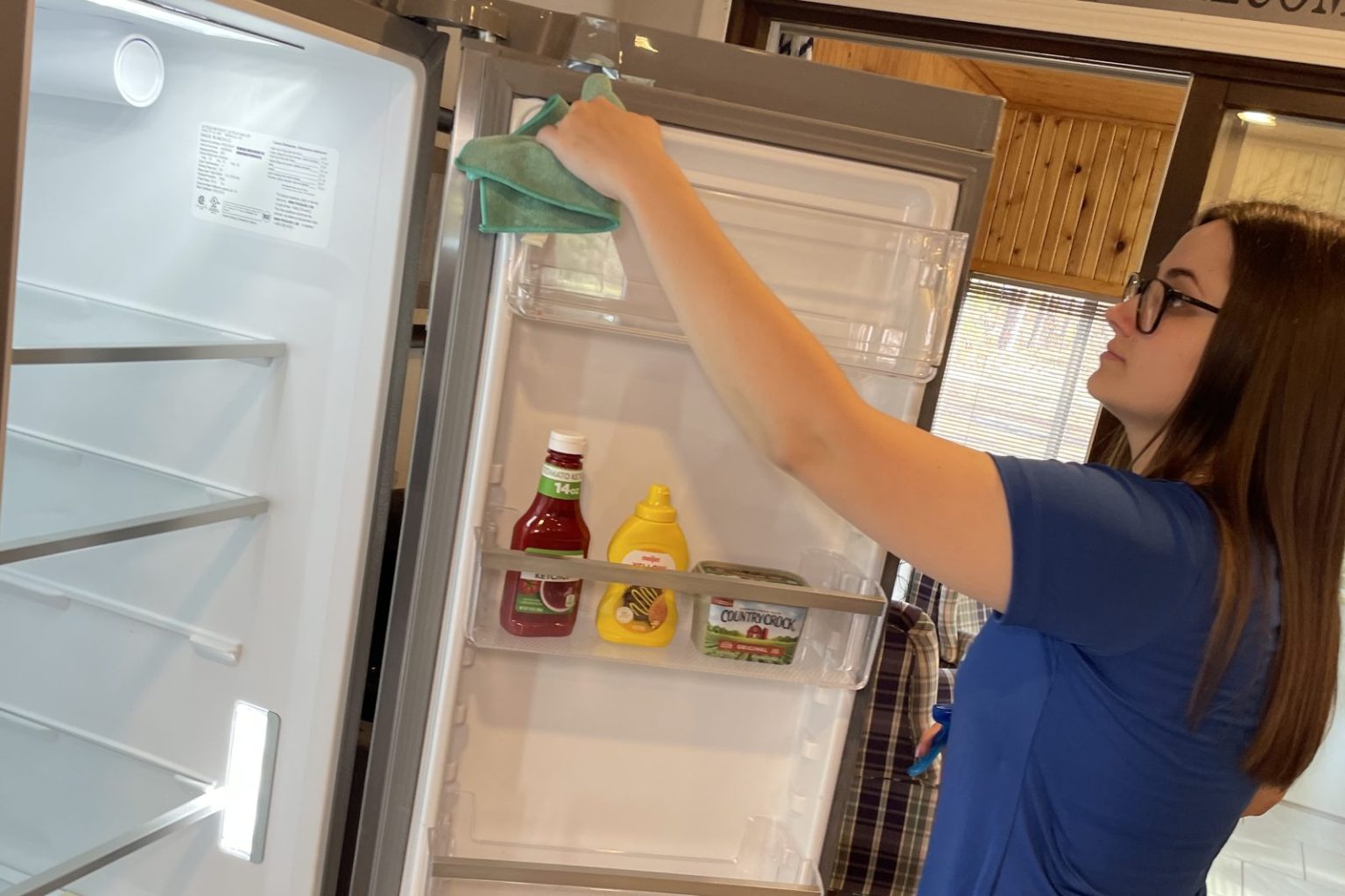 Harbor Shores cleaner wiping the inside of a refrigerator door