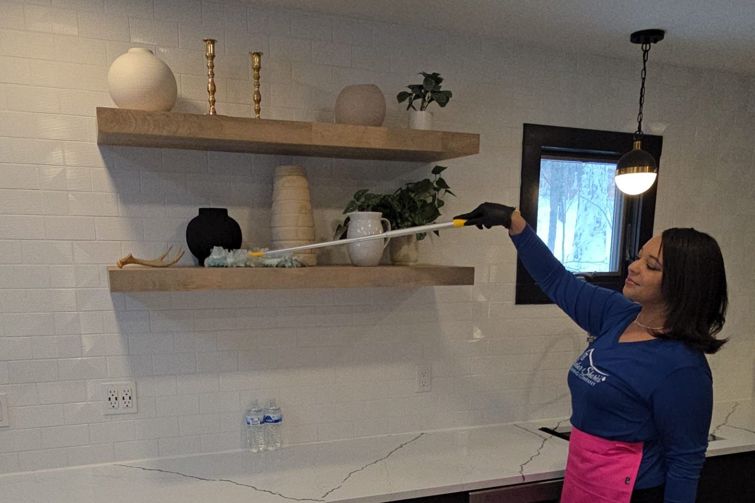 Harbor Shores cleaner dusting floating kitchen shelves with an extension duster
