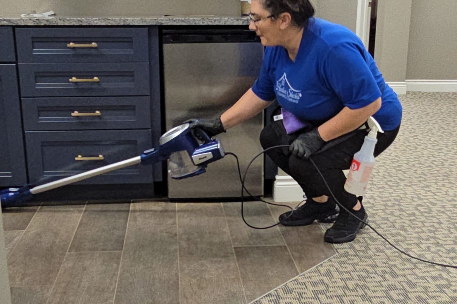Harbor Shores cleaner vacuuming along office kitchenette cabinets