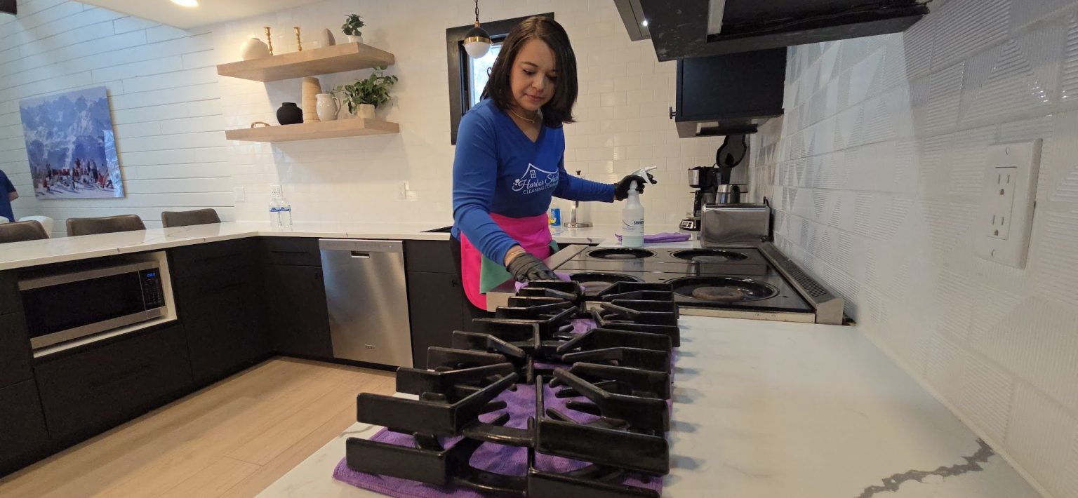 Harbor Shores cleaner deep cleaning a gas range in a modern Northern Michigan kitchen